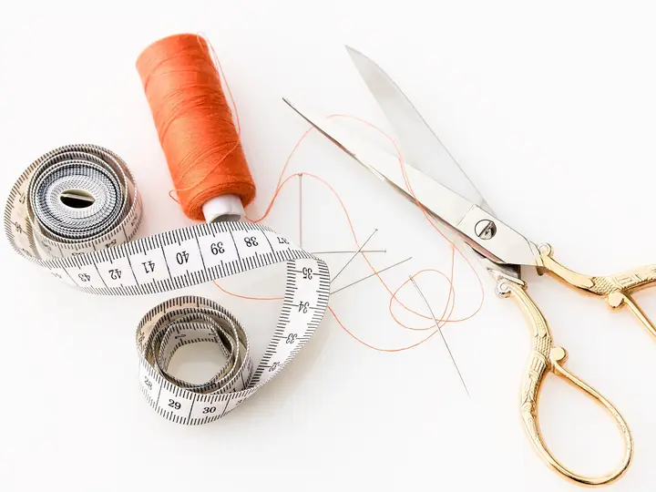 Tailoring scissors, thread and a measuring tape