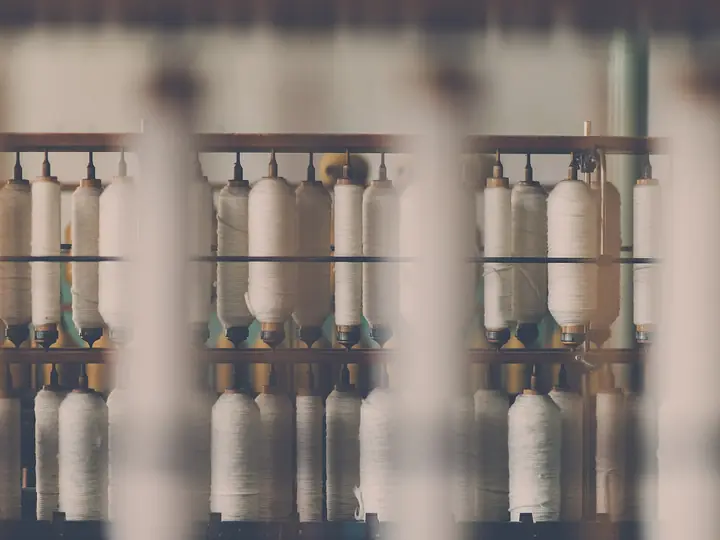 Rows of white cotton yarn cones on a spinning frame